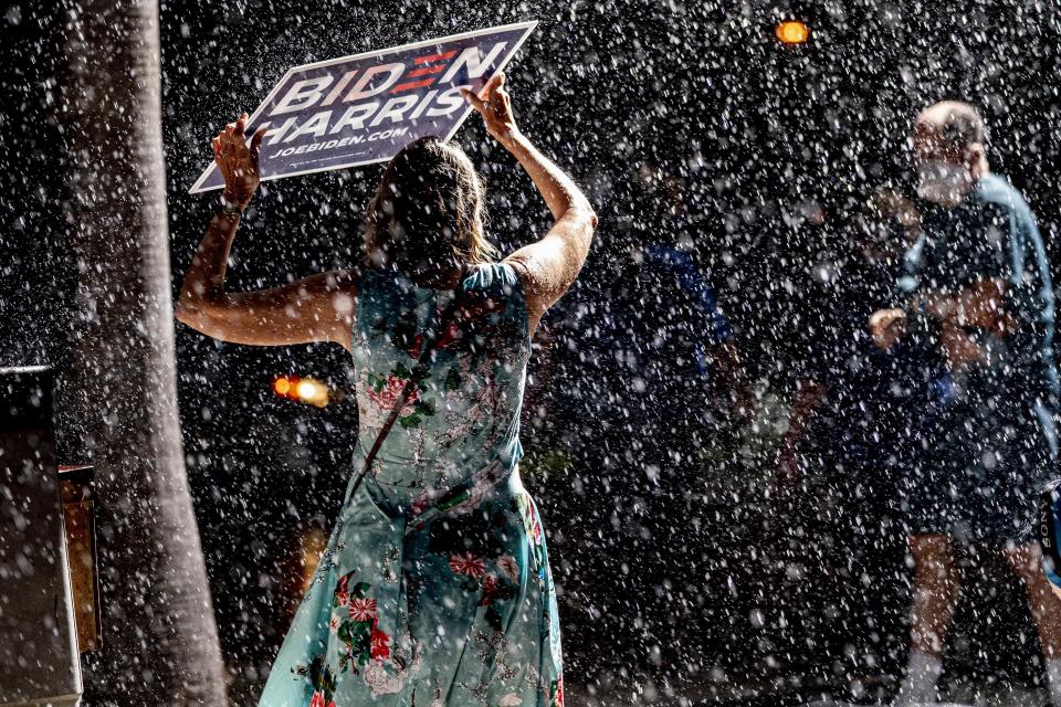 Members of the audience take cover as a sudden downpour cuts short a rally for Democratic presidential candidate former Vice President Joe Biden at the Florida State Fairgrounds in Tampa, Fla., Thursday, Oct. 29, 2020. (AP Photo/Andrew Harnik)