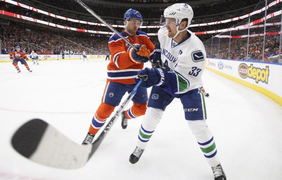 Vancouver Canucks’ Henrik Sedin (33) is checked by Edmonton Oilers’ Adam Larsson. (Jason Franson/The Canadian Press via AP)