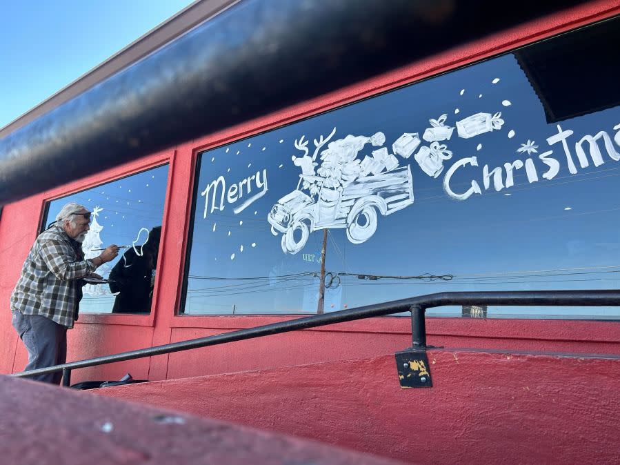 Gary Locklier paints the windows in the front of Cafe 290 in Manor. (KXAN: Frank Martinez)
