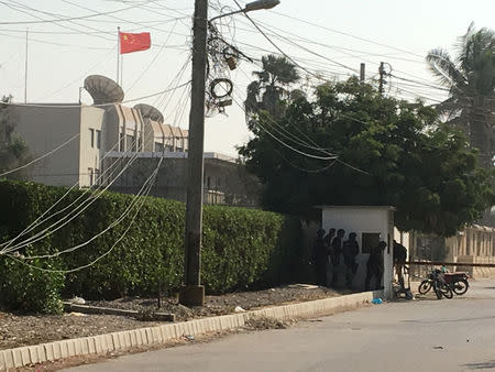 Paramilitary forces and police take cover behind a wall during an attack on the Chinese embassy, where blasts and shots are heard, in Karachi, Pakistan November 23, 2018. REUTERS/Akhtar Soomro