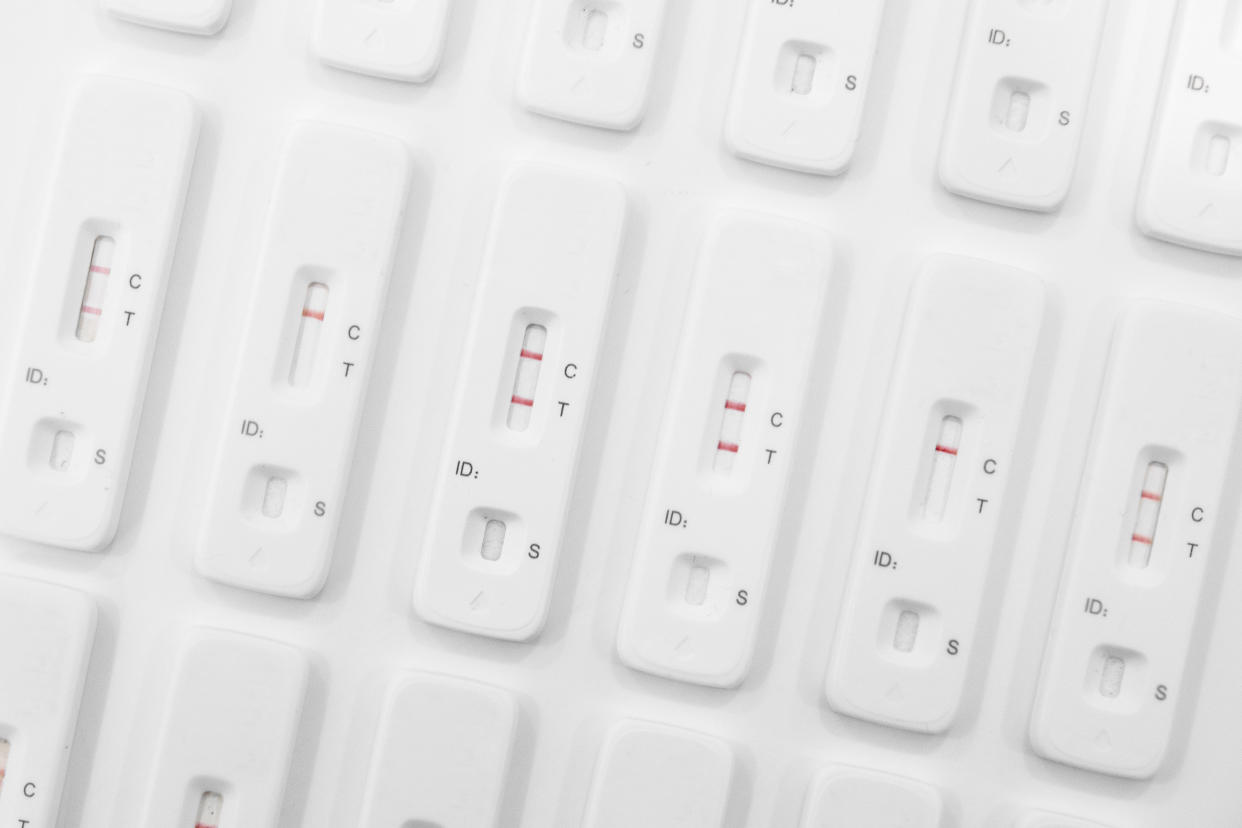 Abstract photo of rows of used Lateral Flow Tests - several showing positive results