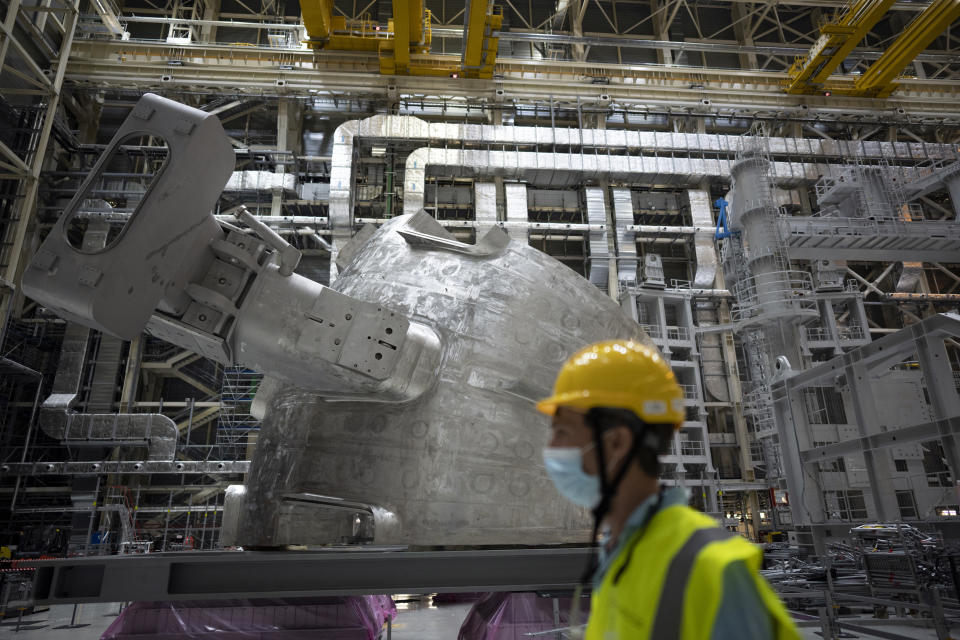 A worker walks past a vacuum vessel component of the ITER machine in Saint-Paul-Lez-Durance, France, Thursday, Sept. 9, 2021. Scientists at the International Thermonuclear Experimental Reactor in southern France took delivery of the first part of a massive magnet so strong its American manufacturer claims it can lift an aircraft carrier. (AP Photo/Daniel Cole)