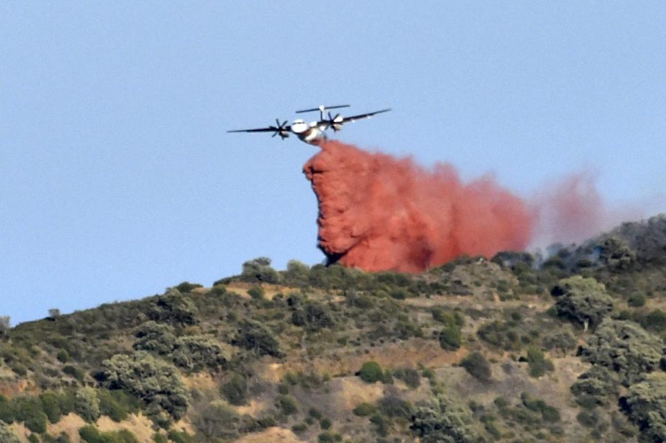 A plane drops fire retardant over a forest fire on a hill near the village of Banyuls-sur-Mer (AFP via Getty Images)