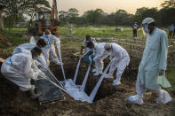 FILE - In this April 25, 2021, file photo, relatives and municipal workers in protective suit bury a COVID-19 victim in Gauhati, India. Despite clear signs that India was being swamped by another surge of coronavirus infections, Prime Minister Narendra Modi refused to cancel campaign rallies, a major Hindu festival and cricket matches with spectators. The crisis has badly dented Modi’s carefully cultivated image as an able technocrat. (AP Photo/Anupam Nath, File)