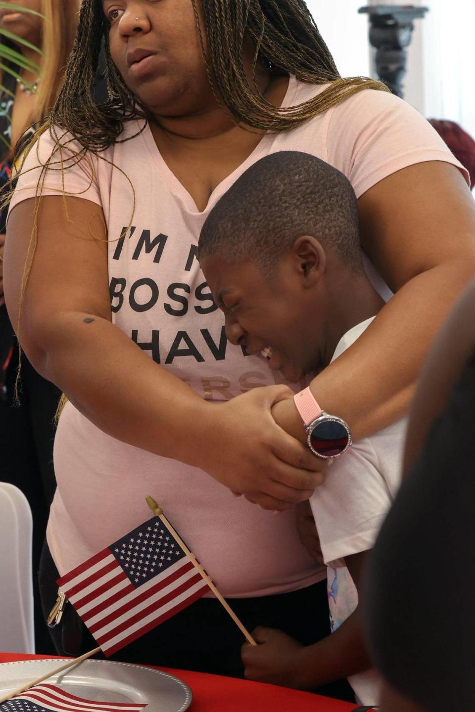 Holding a small American flag, Shavarius Johnson, 11, is comforted by his sister Ericka Pollick, right during the singing of the National Anthem at the commencement of the commemorative ceremony for Sgt. La David T. Johnson.