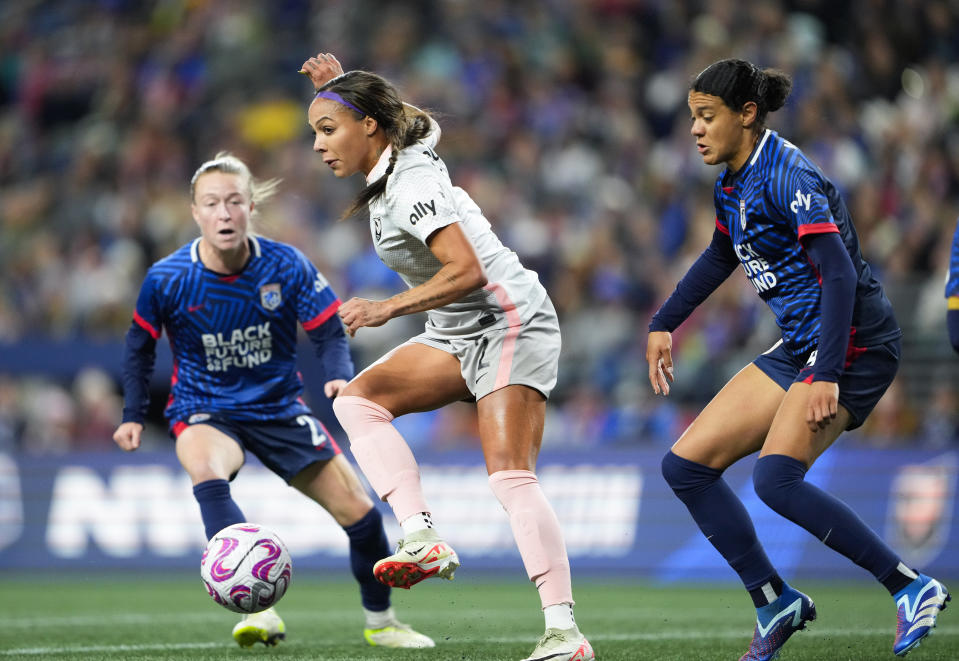 Angel City FC forward Sydney Leroux, center, makes a short pass in front of the goal against OL Reign defender Emily Sonnett, left, and defender Alana Cook, right, during the first half of an NWSL quarterfinal playoff soccer match Friday, Oct. 20, 2023, in Seattle. (AP Photo/Lindsey Wasson)