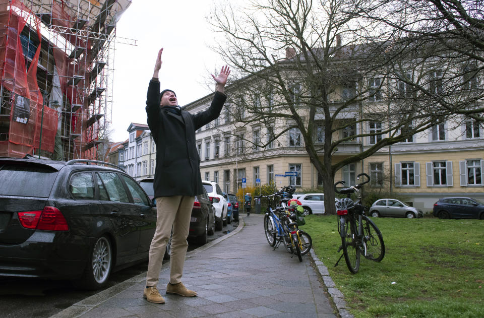 Silvius von Kessel, cathedral organist, choirmaster and composer of Erfurt Cathedral, conducts residents playing and singing 'By loving forces silently surrounded...' by Dietrich Bonhoeffer on their balconies and windows, as people practice social distancing due to coronavirus in Erfurt, central Germany, Sunday, March 29, 2020. For most people, the new coronavirus causes only mild or moderate symptoms, such as fever and cough. For some, especially older adults and people with existing health problems, it can cause more severe illness, including pneumonia. (AP Photo/Jens Meyer)