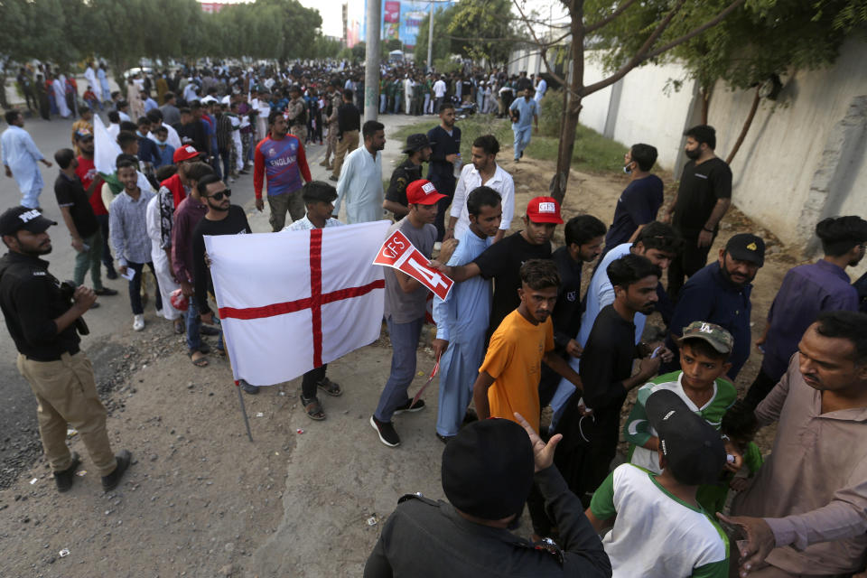 A Cricket fan displays an English cricket flag as people wait to enter in the National Stadium for first twenty20 cricket match between Pakistan and England, in Karachi, Pakistan, Tuesday, Sept. 20, 2022. (AP Photo/Fareed Khan)