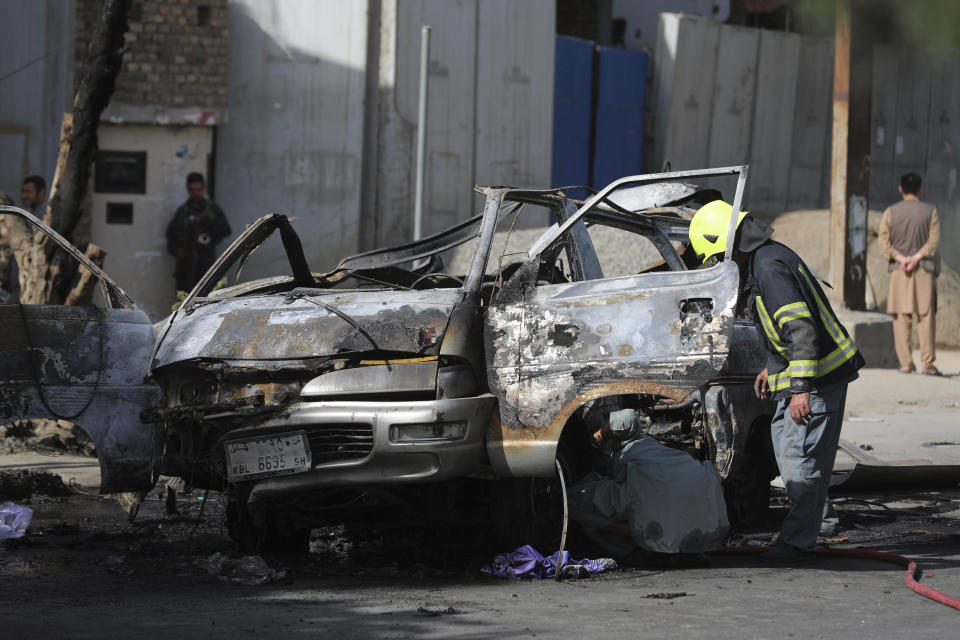 Afghan security personnel inspect the site of a bomb explosion in Kabul, Afghanistan, Saturday, June 12, 2021. Separate bombs hit two minivans in a mostly Shiite neighborhood in the Afghan capital Saturday, killing several people and wounding others, the Interior Ministry said. (AP Photo/Rahmat Gul)