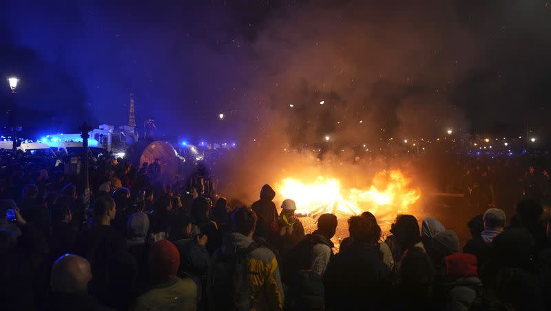 Demonstrators gather next to a burning barricade as they stage a protest in Paris, Friday, March 17, 2023. Protests against French President Emmanuel Macron’s decision to force a bill raising the retirement age from 62 to 64 through parliament without a vote disrupted traffic, garbage collection and university campuses in Paris as opponents of the change maintained their resolve to get the government to back down.