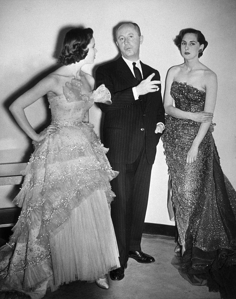 Pictured is Christian Dior with two models wearing his designs.