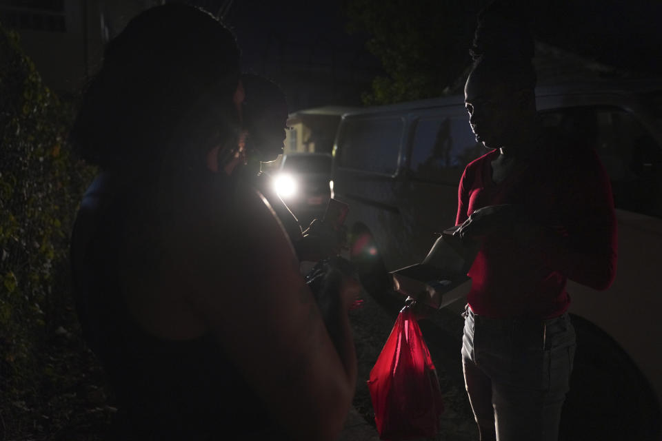 Orden David voluntarily distributes condoms to sex workers, early Saturday, May 13, 2023, in St. John's, Antigua. (AP Photo/Jessie Wardarski)