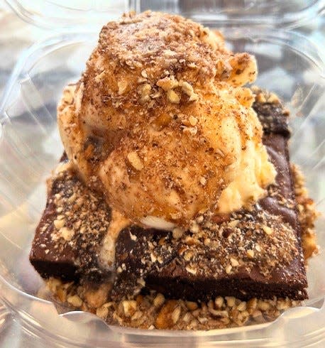 A brownie with a scoop of vanilla ice cream topped with fudge, caramel and loaded with pecans at Whipped Creamery located in Martinez at 353 Furys Ferry Rd.