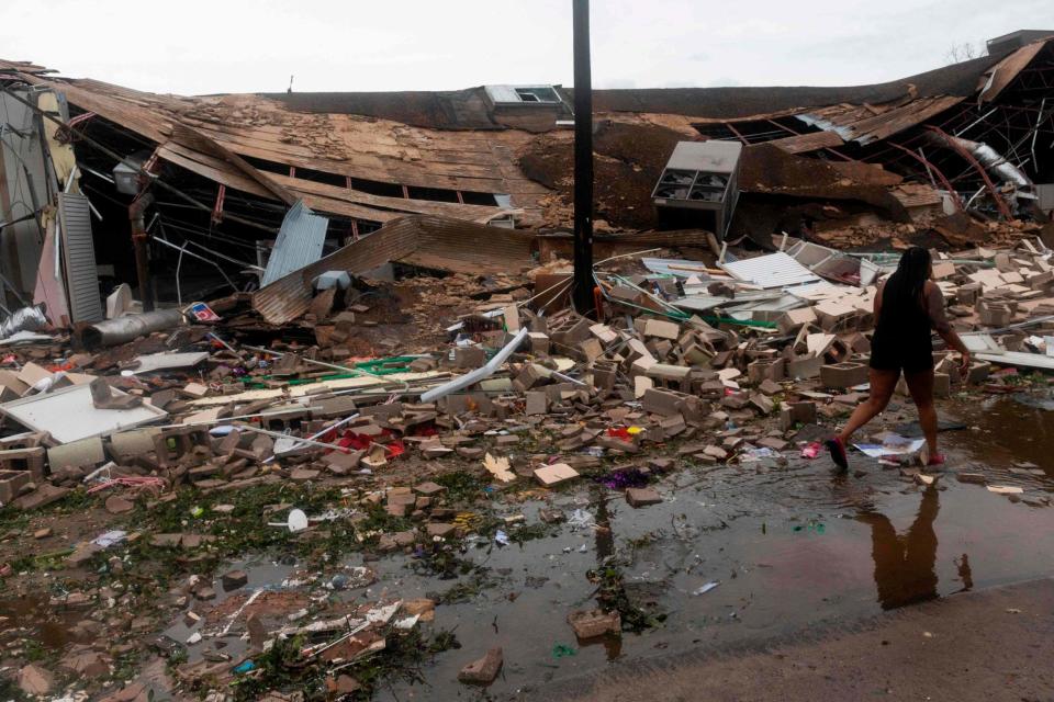 People walk past a destroyed building after the passing of Hurricane Laura in Lake Charles (AFP via Getty Images)