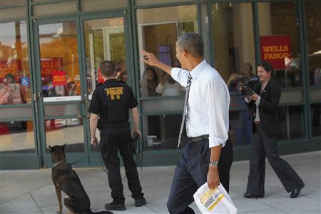 U.S. President Barack Obama waves at people in a bank vestibule after he and Vice President Joe Biden (not pictured) bought lunch at a sandwich shop near the White House in Washington, October 4, 2013. REUTERS/Jonathan Ernst