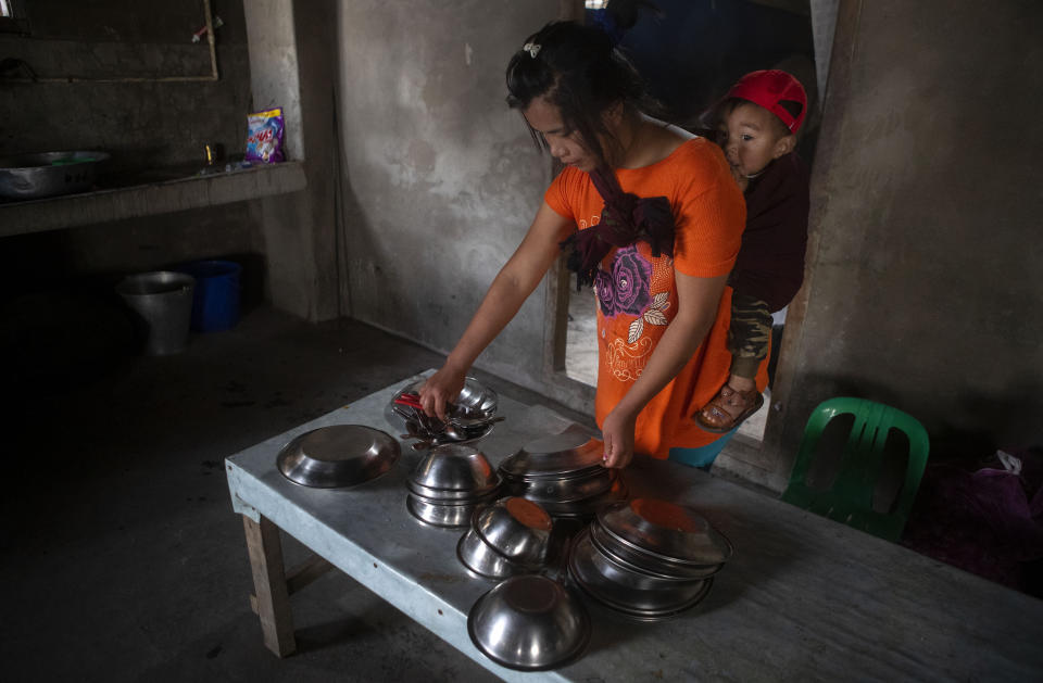 Wife of police officer who fled Myanmar following a military coup carrying her child on her back, arranges utensils at an undisclosed place in Mizoram, a state bordering Myanmar, India, Friday, March 19, 2021. Several Myanmar police officers who fled to India after defying army orders to shoot opponents of last month’s coup in their country are urging Prime Minister Narendra Modi’s government to not repatriate them and provide them political asylum on humanitarian grounds. (AP Photo/Anupam Nath)