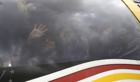 Palestinians returning to Gaza wave as they look out a bus window at the Rafah border crossing between Egypt and southern Gaza Strip November 26, 2014. REUTERS/Ibraheem Abu Mustafa