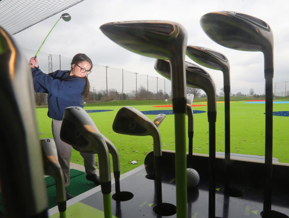 Nevaeh Smart, a waitress at Firestone Country Club, takes a swing at BIgShots Golf on Wednesday during employee day. The high-tech entertainment and dining venue is holding its grand opening on Saturday.