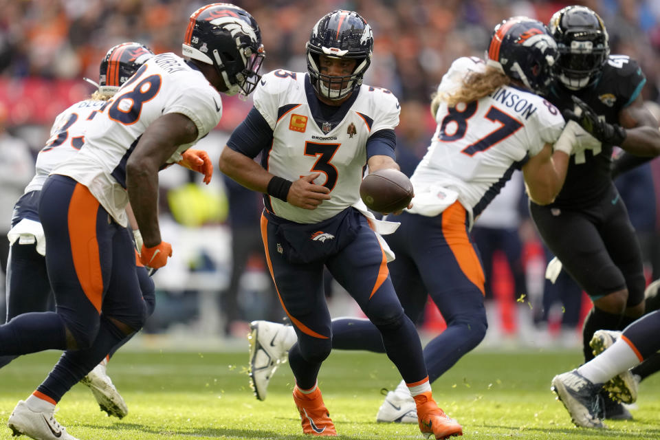 Denver Broncos quarterback Russell Wilson (3), centre, hands the ball over during the NFL football game between Denver Broncos and Jacksonville Jaguars at Wembley Stadium London, Sunday, Oct. 30, 2022. (AP Photo/Kirsty Wigglesworth)