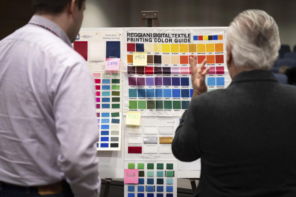 Commission member Aaron Wittnebel and Chair Luis Fitch looked over color charts at the start of the session to narrow down the new state flag choices, Friday, Dec. 15, 2023, in St. Paul, Minn. A state commission selected a basic design concept Friday for a new state flag for Minnesota to replace a current design that's considered offensive to Native Americans, but will need more time to add the finishing touches. (Glen Stubbe/Star Tribune via AP)