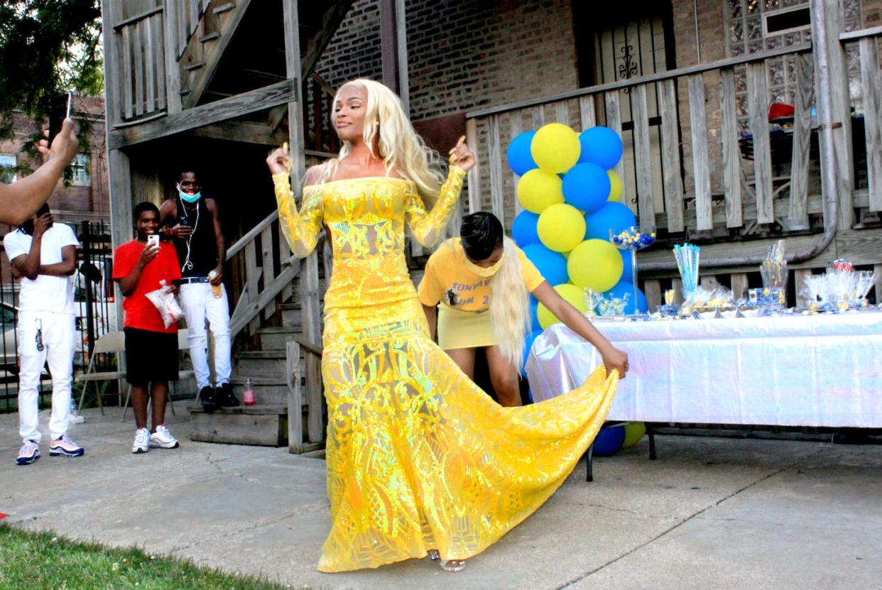 Tonayvia Turner, 18, celebrating 2020 prom send-off in the backyard as her younger sister, Cece, fixes the train on her gown. Jovan Garvi