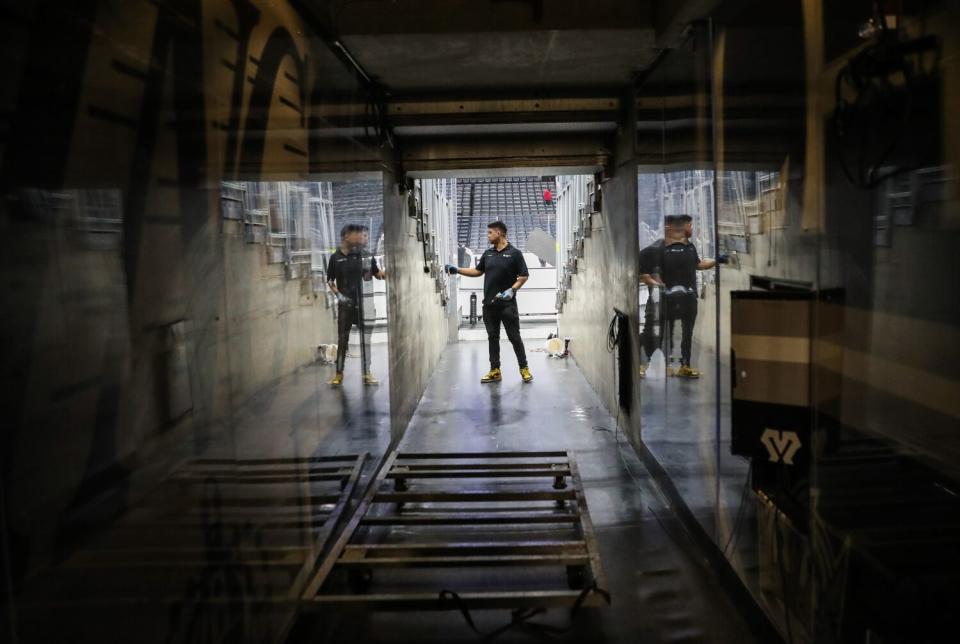 An employee at the Crypto.com Arena secures plexiglass panels in a seating area next to the team tunnel.