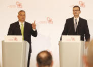 Hungarian Prime Minister Viktor Orban,left, speaks at a join news conference with Poland's Prime Minister Mateusz Morawiecki,right, following talks of government leaders of the Visegrad Group of regional cooperation that also includes the Czech Republic and Slovakia, in Warsaw, Poland, on Friday, July 3, 2020. Poland, which took the group's 12-month rotating presidency, is seeking a generous EU budget to help the region recover from the coronavirus pandemic.(AP Photo/Czarek Sokolowski)