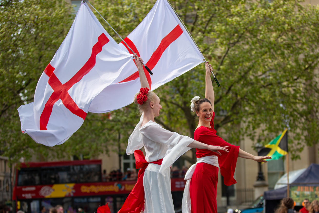 Entertainers on stilts hold English flags at St George's Day celebrations in Trafalgar Square