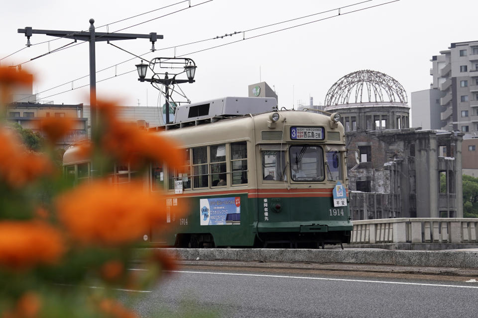 A running tram is seen near the Atomic Bomb Dome in Hiroshima, western Japan, Monday, Aug. 3, 2020. A tram which survived the Hiroshima atomic bombing will run, without any passenger, on the streets on Aug. 6 to commemorate the day of atomic bombing in the city. (AP Photo/Eugene Hoshiko)