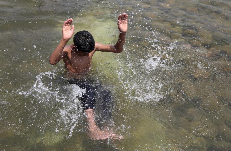 A boy cools off during the heatwave at the Suhrawardy Udyan water reserve in Dhaka (EPA)