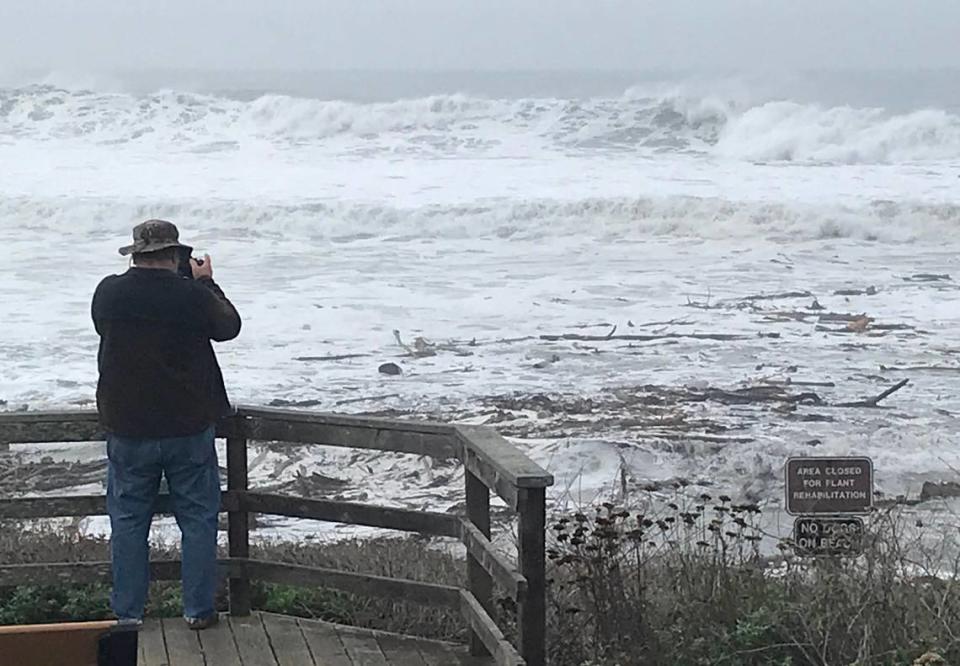 At the Santa Rosa Creek overlook vista point on Moonstone Beach in Cambria, Jim Keally of Arizona captures images of big waves Thursday, Dec. 28, 2023, as the pounding ocean, carrying lots of driftwood, meets flowing creek water.