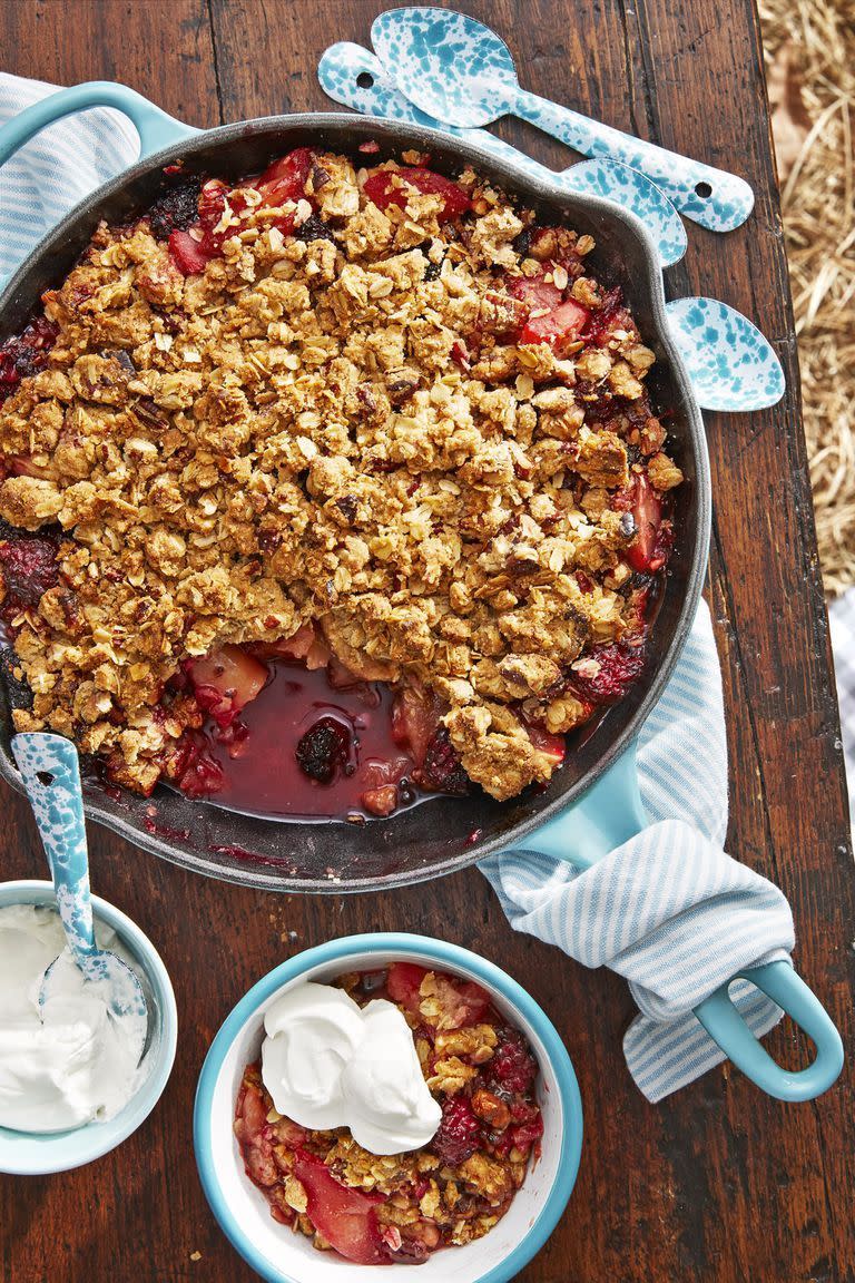 blackberry crumble in a blue enamel cast iron still with a bowl of whipped cream on the side for serving