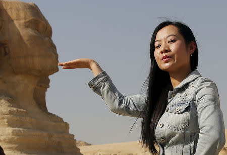 FILE PHOTO: A Chinese tourist poses for a photo in front of the Sphinx at the Giza Pyramids on the outskirts of Cairo, Egypt March 2, 2016. REUTERS/Amr Abdallah Dalsh/File Photo