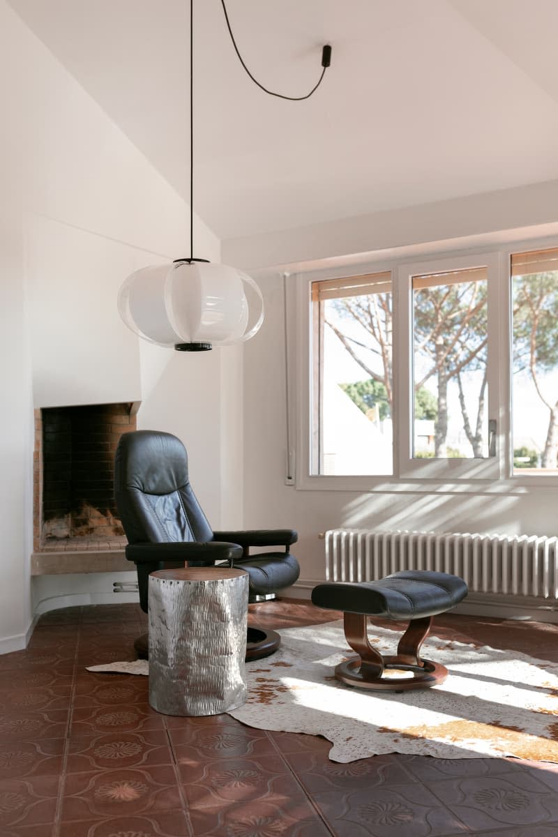 Pendant hanging above armchair in sunny room.