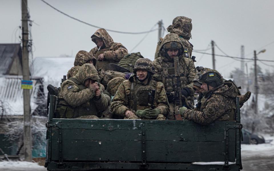 Ukrainian servicemen sit on the bed of a truck while driving in the Donetsk region
