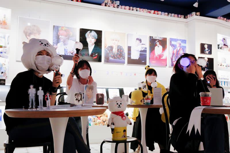 Fans of K-pop idol boy band BTS enjoy as they watch a live streaming online concert, wearing a protective masks at a cafe, in Seoul