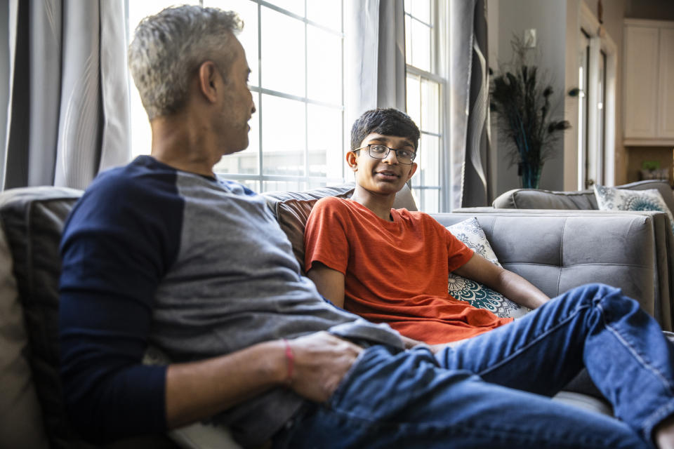 Father and son talking on couch at home