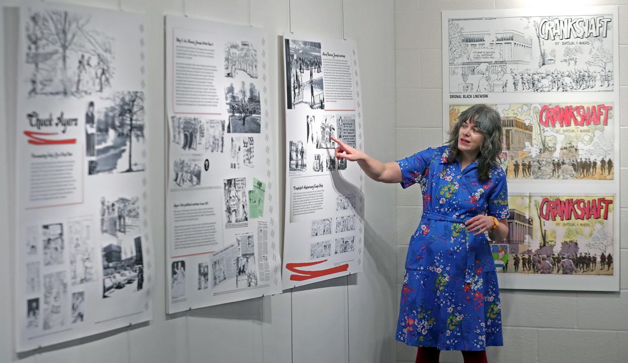 Alison Caplan, director of the May 4 Visitors Center, goes over some of the political cartoons drawn by Chuck Ayers that are included in "Graphic Content: Comics of May 4" that runs until June 7 inside Taylor Hall on the Kent State campus.