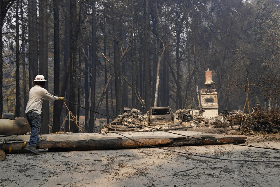 A Pacific Gas & Electric worker moves a downed power line after the CZU Lightning Complex Fire went through Sunday, Aug. 23, 2020, in Boulder Creek, Calif. (AP Photo/Marcio Jose Sanchez)