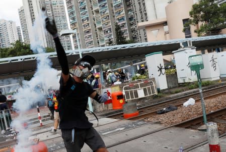 A protester throws back a tear gas canister at the police during a demonstration in support of the city-wide strike and to call for democratic reforms at Tin Shui Wai in Hong Kong