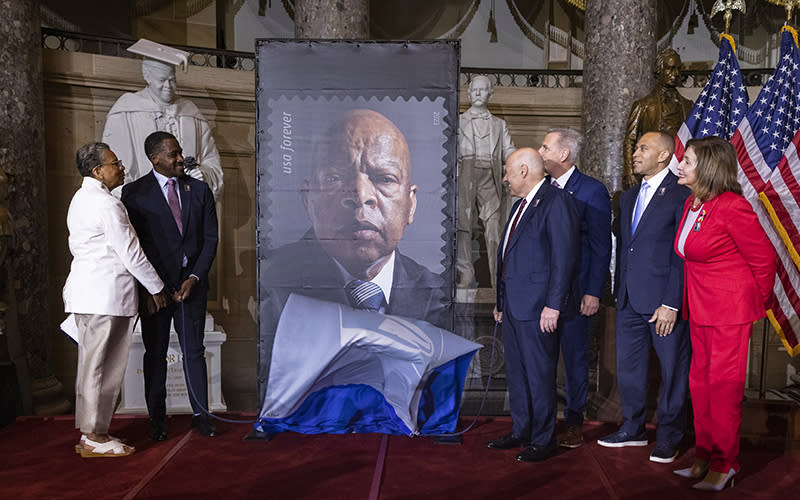 Congressional leaders and officials unveil a stamp in honor of Rep. John Lewis (D-Ga.). A large version of the stamp is shown on a display board while attendees stand on either side of it