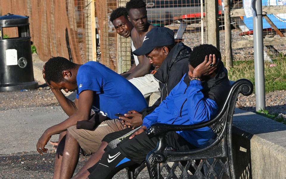 Migrants pictured drying on Kent bench after dumping their stolen dinghy  - Steve Finn