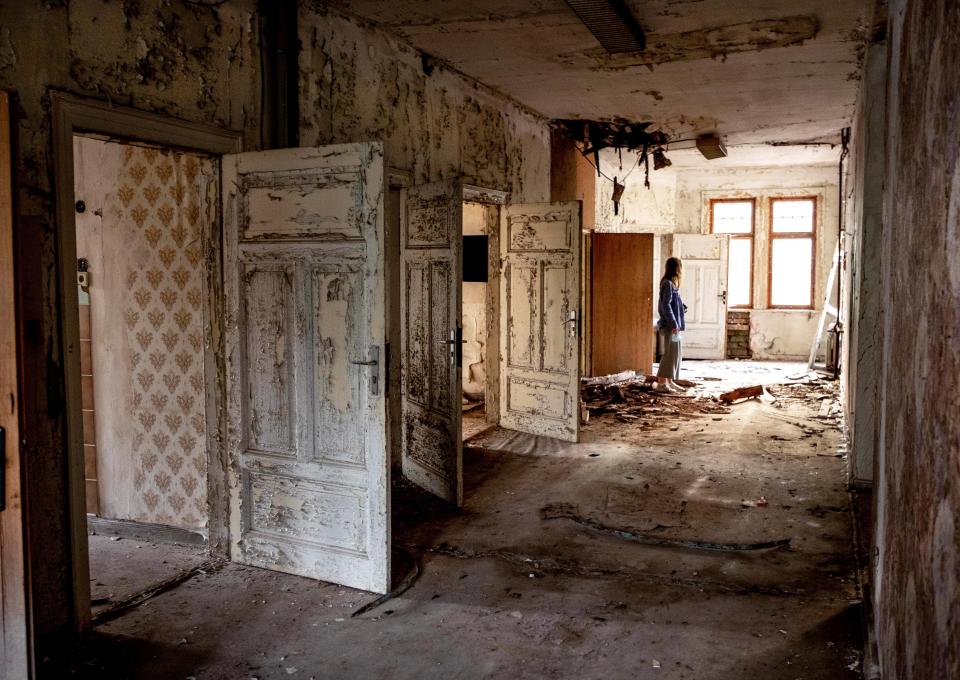 A woman stands in a wrecked and abandoned villa built in 1900 near Eisenach, eastern Germany, Monday, Sept. 21, 2020. Thirty years after Germany was reunited on Oct. 3, 1990, many once-decrepit city centers in the formerly communist east have been painstakingly restored and new factories have sprung up. But many companies and facilities didn't survive the abrupt transition to capitalism inefficient companies found themselves struggling to compete in a market economy, while demand for eastern products slumped and outdated facilities were shut down. (AP Photo/Michael Probst)