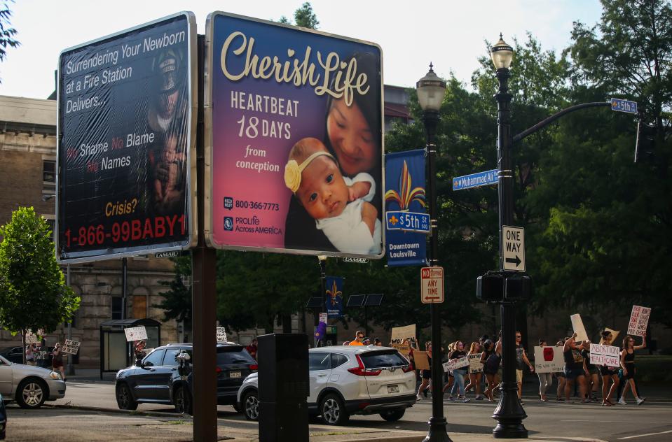 In the shadow of an anti-abortion billboard at the corner of Muhammad Ali Boulevard and Fifth Street in Louisville, abortion rights supporters protest the U.S. Supreme Court's decision that overturned Roe v. Wade. July 4, 2022