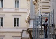 A worker stands on a scaffolding of a building in Rome