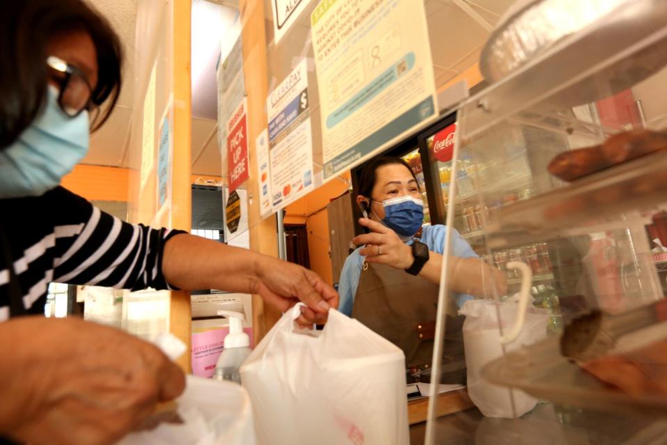 Beth Villago, right, owner of Little Ongpin restaurant, helps a customer.