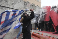 A demonstrator uses the Greek flag to battle riot police during a rally in Athens, Sunday, Jan. 20, 2019. Greece's Parliament is to vote this coming week on whether to ratify the agreement that will rename its northern neighbor North Macedonia. Macedonia has already ratified the deal, which, polls show, is opposed by a majority of Greeks. (AP Photo/Yorgos Karahalis)