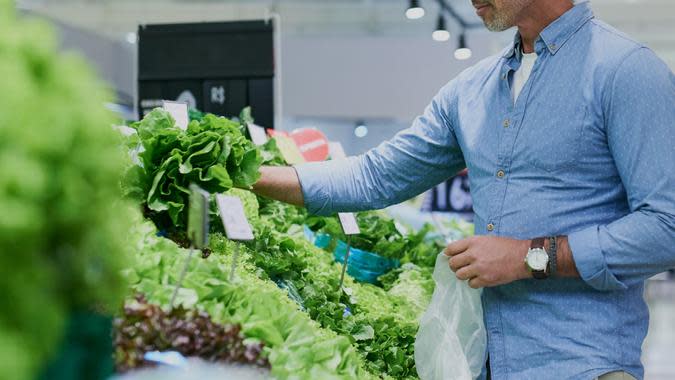 A man choosing lettuce at a store. (Getty Images)
