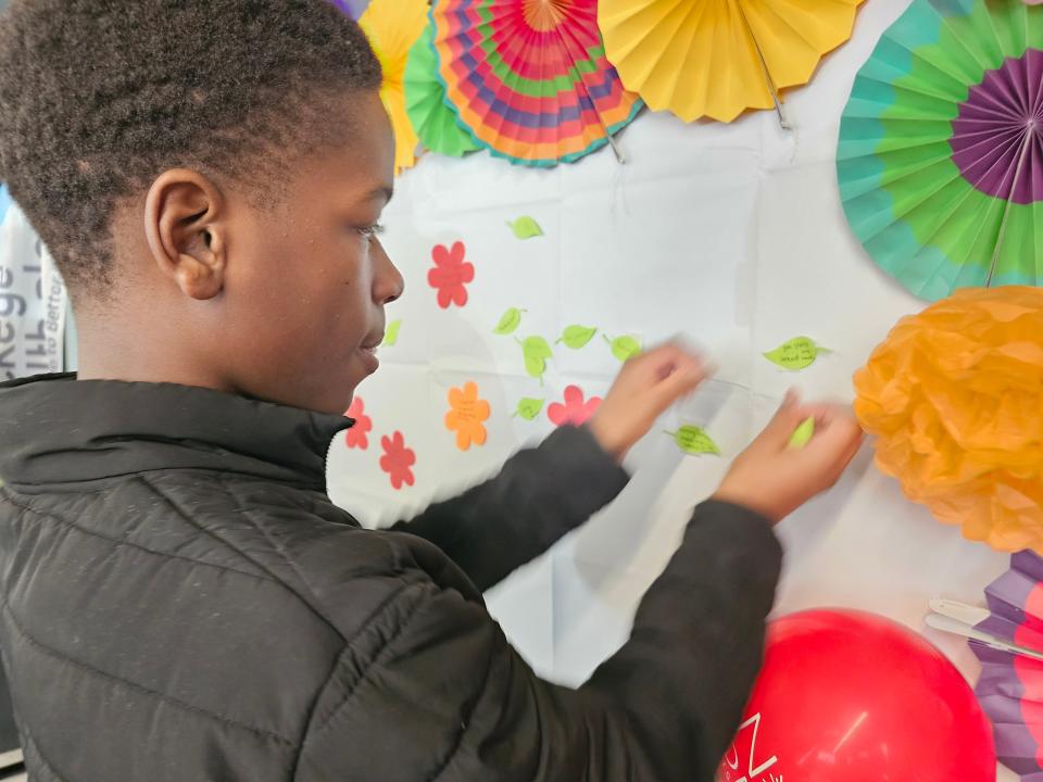 Crenshaw Middle School eighth grader Jai'Vir Randle places leaves on a mural created by students during the No One Eats Alone program. Students wrote ways to make someone feel good, how they can connect with a person and an activity or thing that makes them hopeful.