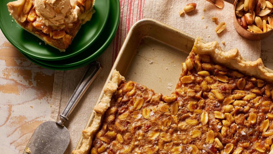 peanut salted caramel slab pie in a matte gold rectangle pan with a pie server and a slice of pie on a green plate